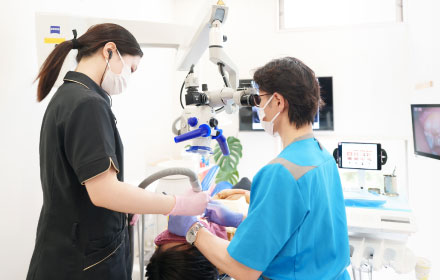 歯科医師がマイクロスコープを使用して診察している写真
